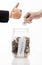 Hand putting Golden coins and seed in clear jar over white background