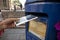 Hand putting a postcard in a Blue Guernsey Post Box unique to Guernsey in the town of St Pierre Port St Peter Port, the main