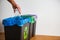 Hand putting single-use plastic bottle into recycling bin