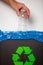 Hand putting single-use plastic bottle into recycling bin