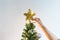 Hand putting sparkling golden star on Christmas tree for decorating and celebration in Christmas Holiday