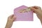 Hand putting Thai money in pink envelope