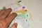 A hand reaches out to fanned out cash bills of Qatar, the currency called the Qatari Riyal notes of cash spread out on the white