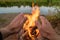 Hand reaching bonfire fire by river to get warm