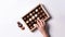 Hand reaching for box of chocolates on white background