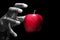 Hand reaching for a red apple, the forbidden fruit