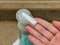 Hand reaching toward a foaming pump soap dispenser near a sink