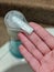 Hand reaching toward a soap dispenser near a sink to cleanse their hands of dirt and germs