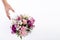 Hand receiving a pastel bouquet from pink and purple gillyflowers and alstroemeria on white