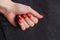 A hand with a red manicure on gray denim background