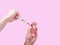 A hand with red nails holds a syringe. Girl holds a syringe for pointed. Medicine. Pink background, place for text.