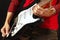 Hand of rock guitarist inserts input jack to electric guitar on black background.