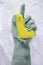 A hand in a rubber glove holds a sponge and wipes soap suds on a glass background. The concept of cleaning, housekeeper services