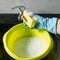 Hand in rubber glove washes sponge in yellow basin. Concept- housework, house cleaning.