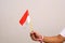 Hand\'s man holding indonesian flag with red whit ribbon on the wrist. Isolated on gray background