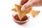 Hand with samosa dipping in sweet and sour sauce isolated on white background.