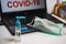 Hand sanitizer bottle and surgical mask on a laptop keyboard that reads covid-19 on the screen. Illustration to protect office