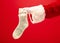 Hand of Santa Claus holding a Christmas Knitted Socks on red background