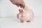 Hand saving a bitcoin coin into a pig peggy bank against a white background. Future investment concept and empty copy space