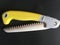 Hand saw for cutting and arranging fruit trees with a yellow handle on a black background,folding saw macro isolated