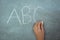 Hand of schoolgirl writing on chalkboard in classroom