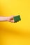 hand with a scourer on yellow background