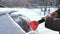 A hand with a scraper in winter cleans the windshield or windshield of a car from snow and ice. Use a scraper or scraper