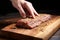 hand seasoning a raw seitan steak on a wooden board