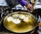 Hand seen pouring pastry into hot oil for a pretzel-like snack