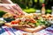 hand selecting chicken club sandwich from a picnic spread