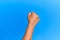 Hand of senior hispanic man over blue isolated background doing protest and revolution gesture, fist expressing force and power