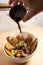 Hand serving balsamic sauce in bowl of Colombian food