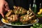 hand serving grilled artichokes on a plate