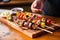 hand serving grilled kebabs on a wooden board