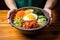 hand serving hot bibimbap bowl on wooden table