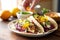 hand setting citrus-glazed fish tacos on a table