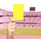 Hand showing a yellow card in front of a stadium