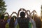 Hand sign heart. A group of people holds hands with a heart sign on a sky background with sunset on nature.