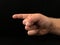 Hand sign, index finger points to the side, on a black background. Gesture with one finger, the direction of the path