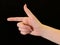 Hand sign, index finger points to the side, on a black background. Gesture with one finger of one hand. Female hand with