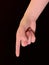 Hand sign, index finger points to the side, on a black background. Gesture with one finger of one hand. Female hand with