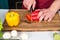 Hand slice pepper with ceramic knife. Vegetables getting cut on wooden cutting board. Food preparation and cooking recipes. Vegeta