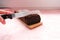 A hand slicing a homemade blueberry cake with a knife, pink background