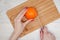 Hand slicing orange on wooden board