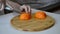 Hand slicing orange on wooden board. Housewife woman slicing fresh orange fruits on cutting board for salad or juicing in kitchen