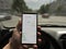 Hand with a smartphone in the car. Looking at phone Google Maps Navigator. Google is the biggest Internet search engine in the
