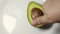 Hand spining avocado on the white plate. Slow motion