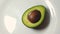 Hand spining avocado on the white plate. slow motion