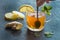 A hand with a spoon stirring into a cup of ginger tea