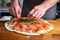 hand spreading cold smoked salmon on homemade pizza dough